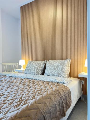 a bedroom with a large bed with a wooden wall at Apartamento La Marina Azul el Puerto de Lo Pagan in San Pedro del Pinatar