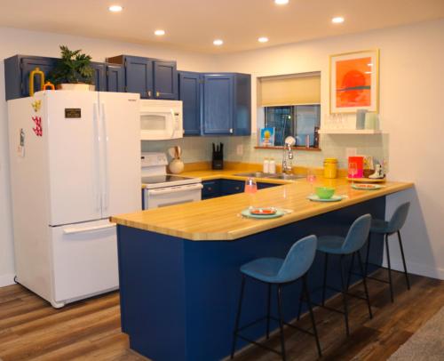 a kitchen with blue cabinets and a white refrigerator at Daylight Cove Lakefront Condo, Pool, Hot Tub! in Lake Ozark