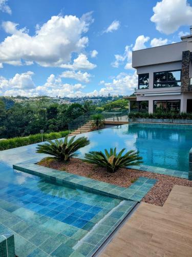 a swimming pool with palm trees in front of a building at Vinícola & Pousada Terragnolo in Bento Gonçalves