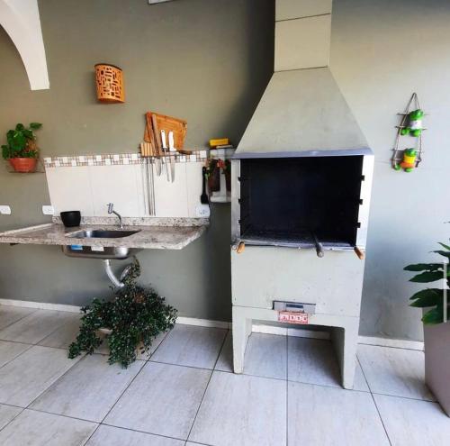 eine Küche mit einer Arbeitsfläche, die mit einem Spülbecken und einem Herd ausgestattet ist in der Unterkunft Hospedaria Litoral in Caraguatatuba