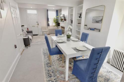 a dining room with a white table and blue chairs at Georgetown Cobblestone Cottage - Private Parking in Washington, D.C.