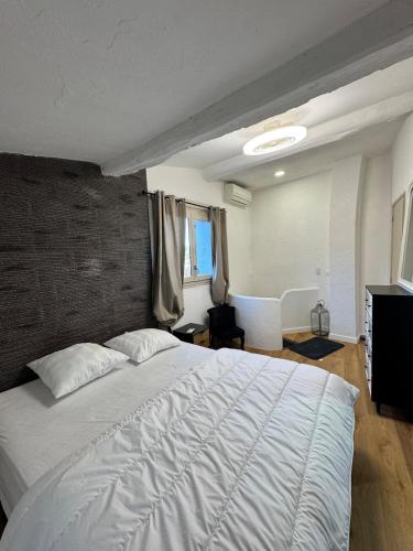 une chambre avec un grand lit blanc avec un mur de briques dans l'établissement Maison de village St Paul de Vence, à Saint-Paul-de-Vence