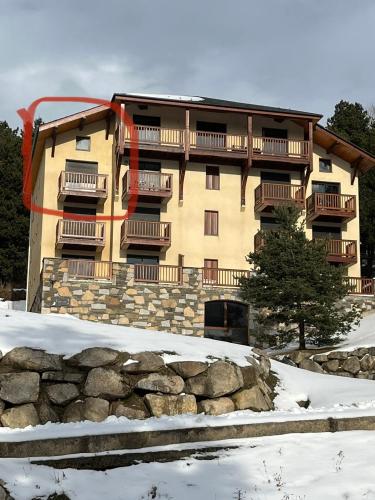 un immeuble avec de la neige devant lui dans l'établissement Le petit Pinson, à Font-Romeu-Odeillo-Via