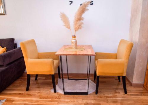 a table with two chairs and a vase on it at Apartman Royal 4 in Doboj