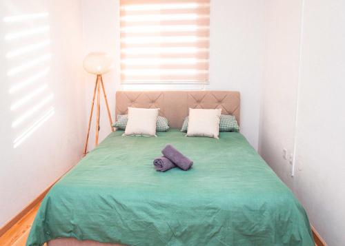 a bed with two pillows and a green blanket at Apartman Royal 4 in Doboj