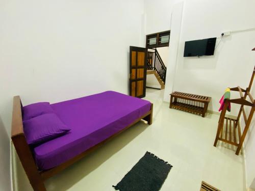 a purple bed in a room with a tv at Sun Palace Yala in Tissamaharama