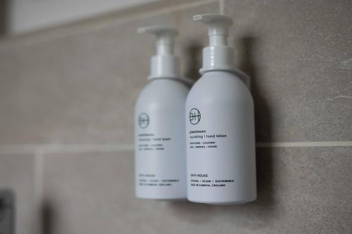 two white bottles of soap sitting on a wall at Southview Spa Windermere in Windermere