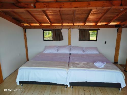 a large bed in a room with two windows at San Luis Cabaña in Curití