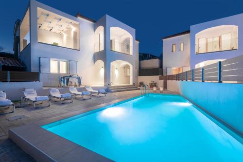 a villa with a swimming pool in front of a house at Astarte Villas - Coral Pool Villa in Plános