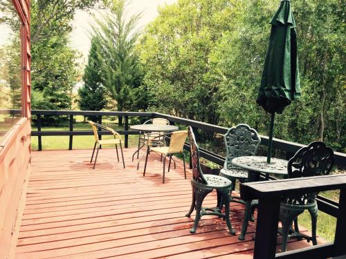 a wooden deck with tables and chairs and an umbrella at Cabañas Natural Park Lodge Pucón in Pucón