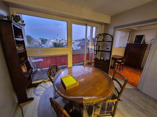 une table et des chaises dans une pièce avec une grande fenêtre dans l'établissement Le Mirabelle - Balcony - Pyrenees View - Expo Fair, à Pau