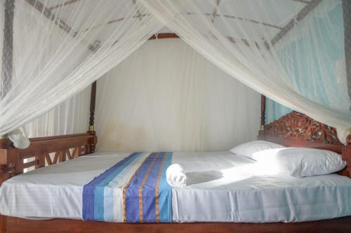 a bedroom with two beds with a canopy at Sunshine Hotel in Hikkaduwa