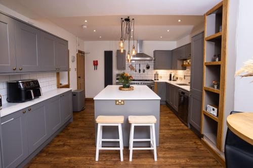 a kitchen with gray cabinets and a white island with stools at Southview Spa Windermere in Windermere