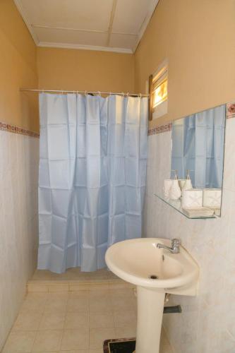 baño con lavabo y cortina de ducha azul en Sunshine Hotel, en Hikkaduwa
