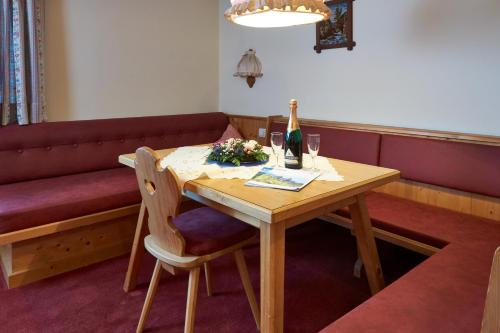 a table with a bottle of wine and two glasses at Apart & Pension Wassermann inklusive Sommerbergbahnticket in Tannheim