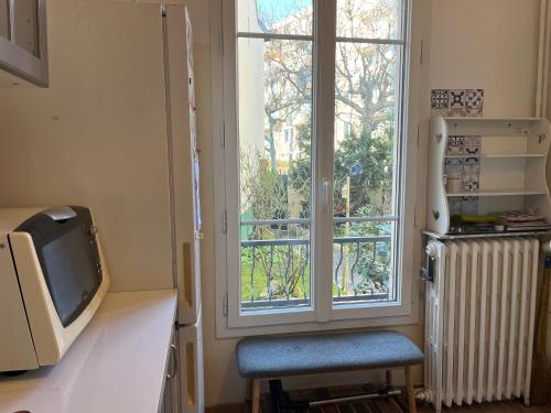 une cuisine avec une fenêtre, une chaise et une télévision dans l'établissement Cozy pavillon quartier Laplace, Maison des examens, à Arcueil