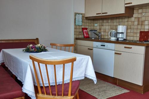 a kitchen with a table with a flower arrangement on it at Apart & Pension Wassermann inklusive Sommerbergbahnticket in Tannheim