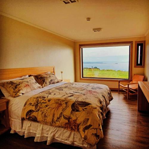 a bedroom with a large bed and a large window at Hotel Nubes de Quinchao in Quinchao