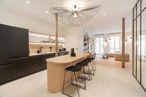 une cuisine avec un bar avec des tabourets et un grand éclairage dans l'établissement Luxury apartment of 140 sqm, à Paris