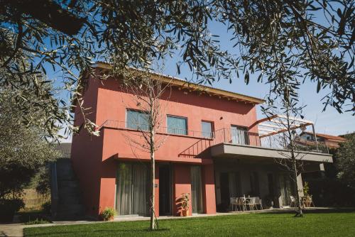 a red house with a tree in front of it at Ampeli Villas in Néa Artáki