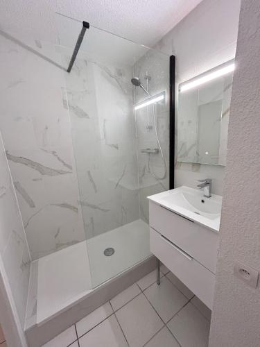une salle de bain blanche avec une douche et un lavabo dans l'établissement Front de mer, 8min du Palais des Festivals, à Cannes