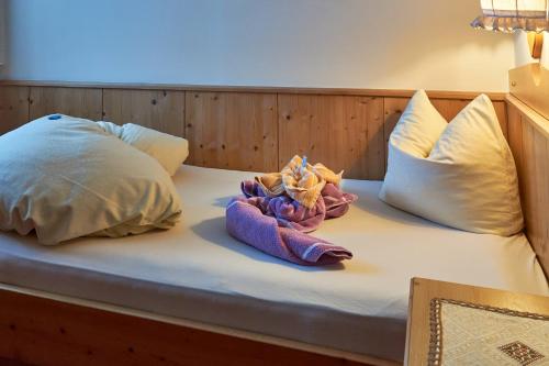 a bed with two pillows and a stuffed animal on it at Apart & Pension Wassermann inklusive Sommerbergbahnticket in Tannheim