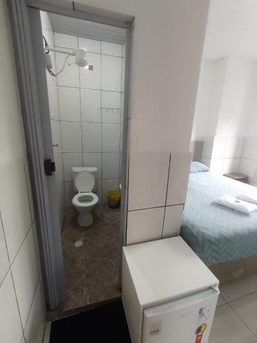 a small bathroom with a toilet and a bed at Hotel Anacleto in São Paulo