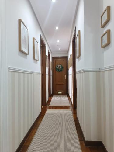 a hallway with white walls and a wooden door at El Capricho de Candás in Candás