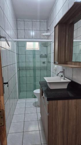 a bathroom with a shower and a sink and a toilet at Pérola de Bombinhas in Bombinhas