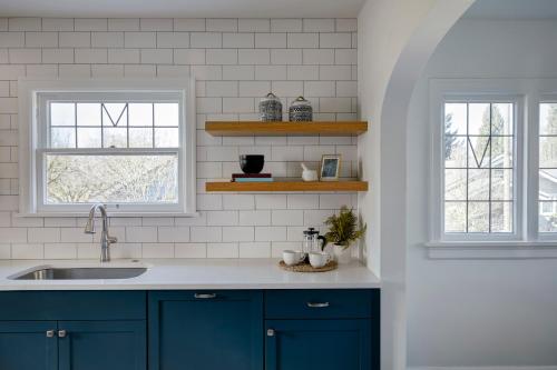 a kitchen with blue cabinets and two windows at Luxe 220, Unit 2 - Front Street Suite in Wilmington