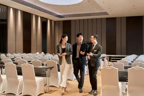 a man and woman walking through a room with chairs at Sheraton Saigon Grand Opera Hotel in Ho Chi Minh City