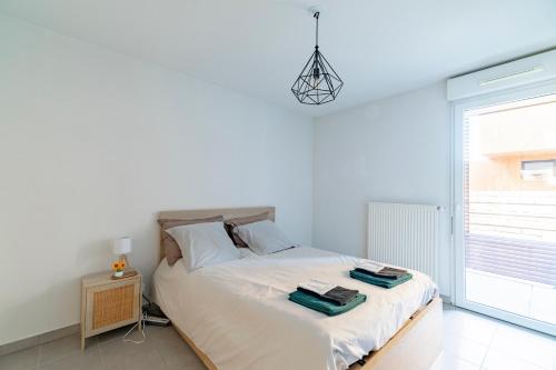 une chambre avec un lit avec des draps blancs et une fenêtre dans l'établissement Appartement charmant au porte de Montpellier, à Saint-Jean-de-Védas