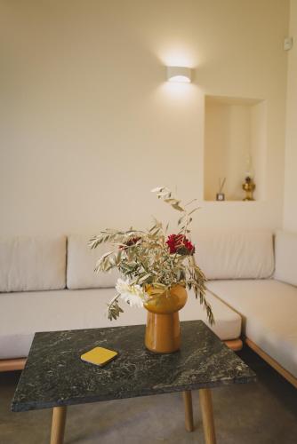 a living room with a table with a vase with flowers at Ampeli Villas in Néa Artáki