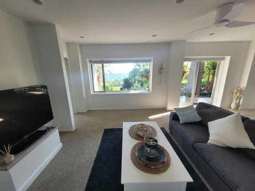 a living room with a couch and a tv at The Beach House in Red Beach