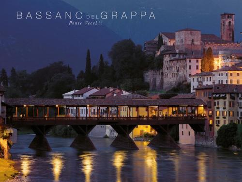 a train crossing a bridge over a river in a city at Borgo Tabari Locazione Turistica in Mussolente 