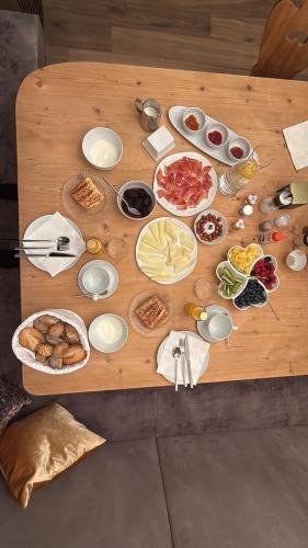 een houten tafel met verschillende soorten voedsel bij Luxury Dolomites Apartments in Dobbiaco