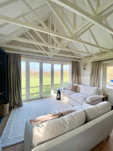 a large living room with white couches and windows at Luxury Boutique retreat, hot tub, dog friendly in Hanmer