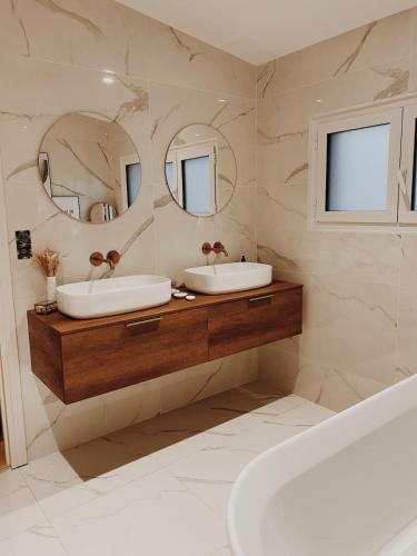 une salle de bain avec deux lavabos et un grand miroir dans l'établissement Villa avec piscine privée au calme, à BIQ