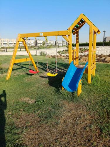 a playground with two swings on the grass at فيلا دوبلكس بالعين السخنة للعائلات فقط in Ain Sokhna