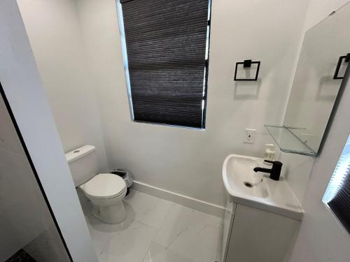 a white bathroom with a toilet and a sink at Cute Private Room - Close to airport & Free parking 01 in Miami