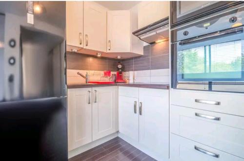 une cuisine avec des armoires blanches et un réfrigérateur noir dans l'établissement La capitainerie, au Cap d'Agde