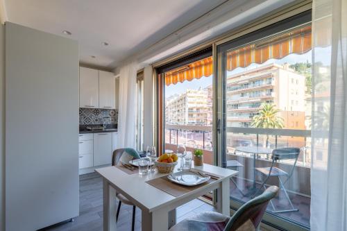 une cuisine et une salle à manger avec une table et une grande fenêtre dans l'établissement Fabuleux appartement 2 personnes au cœur de Menton, Climatisé et Proche Gares routière et SNCF, à Menton