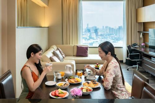 two women sitting at a table eating food at Marriott Executive Apartments Sukhumvit Park, Bangkok in Bangkok