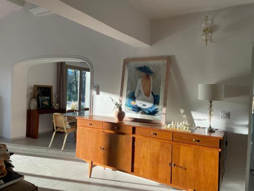 una sala de estar con un tocador de madera con una pintura en la pared en La villa des Carriers- maison avec piscine proche mer, en Roquefort-les-Pins