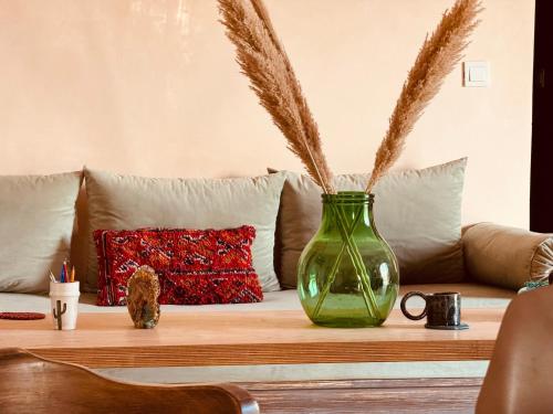 a green vase sitting on a table with a couch at Chambre aux portes du désert I Agafay in Wawizelt