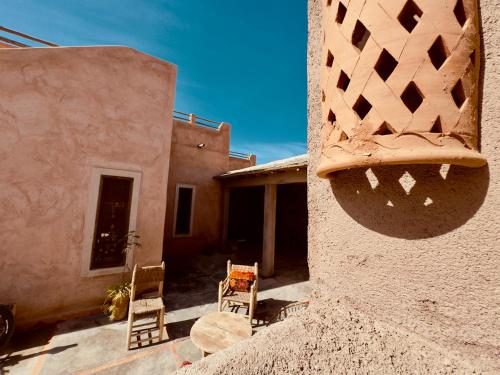 a house with two chairs sitting outside of it at Chambre aux portes du désert I Agafay in Wawizelt