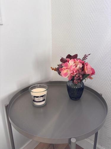 une table en verre avec un vase de fleurs et une bougie dans l'établissement Les Ours - Studio Centre Ville, à Rouen