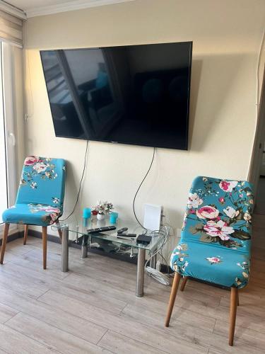 a living room with two chairs and a table and a tv at Depto 3 dormitorios a 10 minutos de la playa Herradura Sindempart in Coquimbo