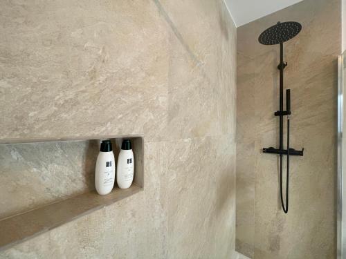 dos botellas de champú sentadas en un estante en una ducha en La villa des Carriers- maison avec piscine proche mer, en Roquefort-les-Pins
