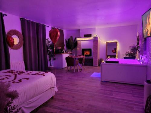 a bedroom with purple lighting and a bed and a table at Suite de charme avec JACUZZI illimité et jardin privatif in Saint-Prix